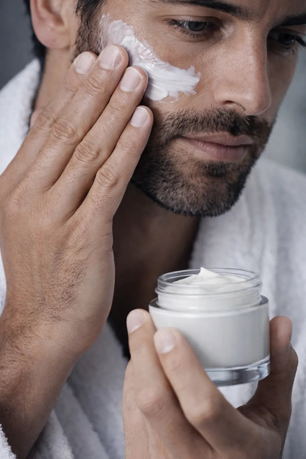 Man applying face cream to his skin as part of a daily men’s skincare routine.